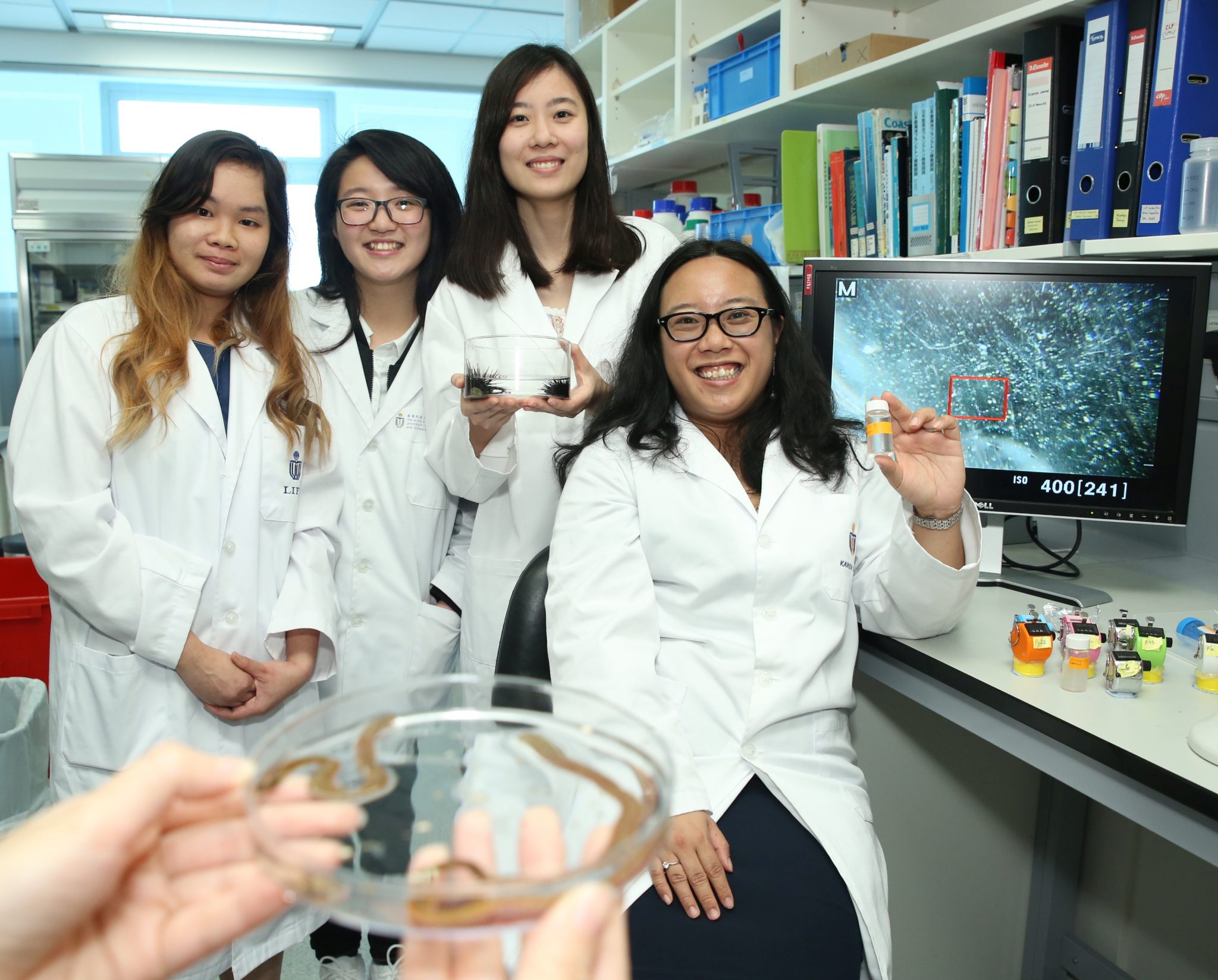  (From right) Prof Karen Chan and her research team members Abby Lo, Ng Pui-lam and Julia Leung discover microbeads’ (bottled) impact on bristle worms (in the Petri dish) and slipper limpets.