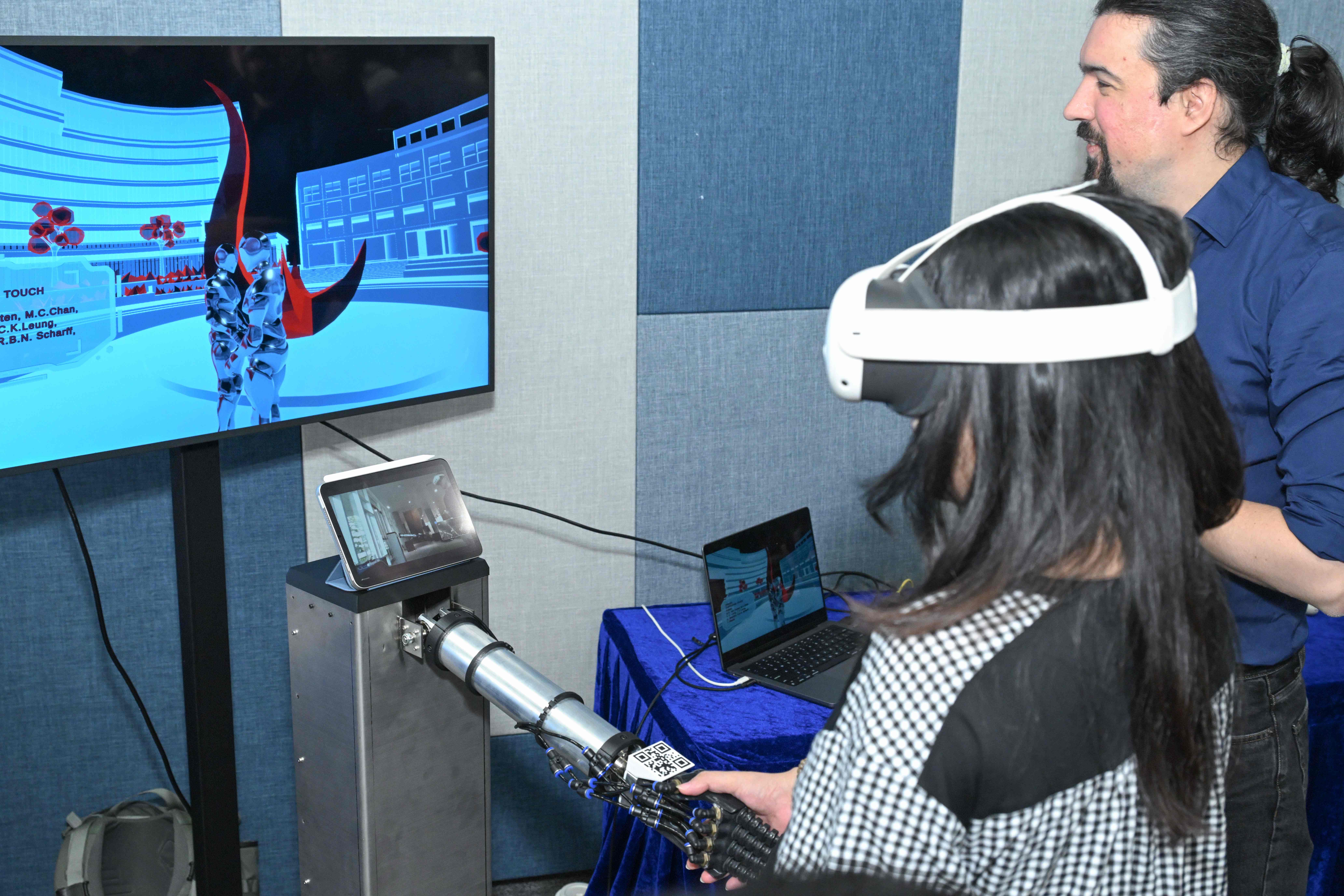 The HKUST XRIM Lab's work, Unfolding Touch, enables a soft-robot-mediated handshake between the Clear Water Bay and Guangzhou campuses, integrating sensing and tactile replication to create a shared touch experience across distance.