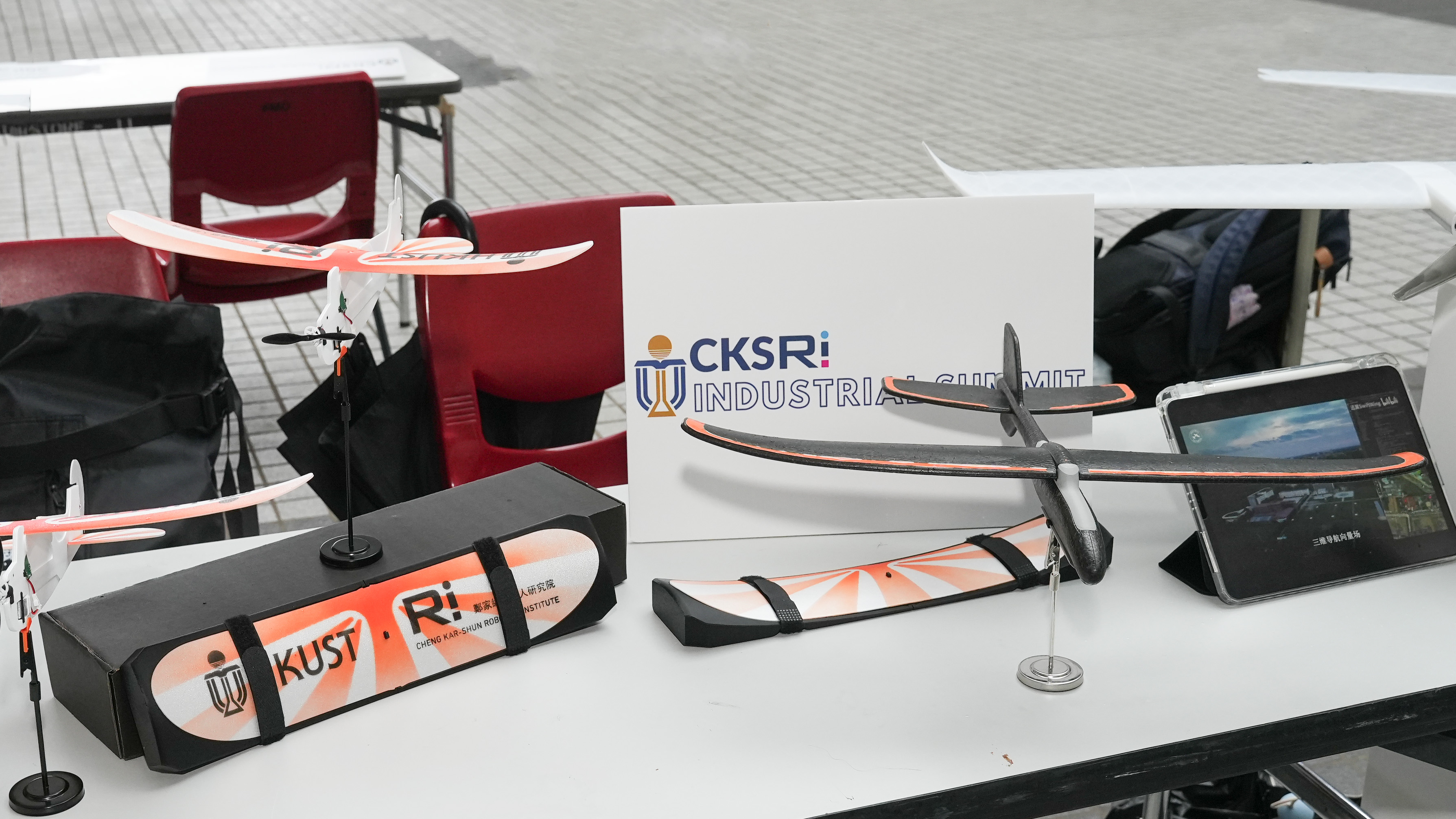 Exhibition booths are set up at the event to showcase the latest technologies developed by HKUST members and various robotics companies. Among them is Universpirit Innovation, which focuses on the development of fixed-wing aircraft. Its technology ranges from lightweight educational plane kits weighing around 8 grams, designed for programming training by primary and secondary school students, to light aircraft weighing about 3 kilograms for applications such as low-altitude transport.